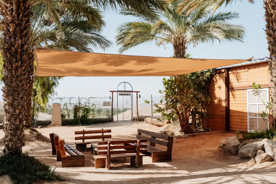 A lounge corner under shade sails, facing the desert gate